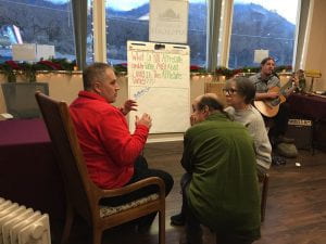Three people engaged in conversation about the wants of the community. There is a board with notes on it in the background.