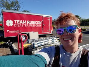 Image of Mae Hollister smiling in front of Team Rubicon trailer. 