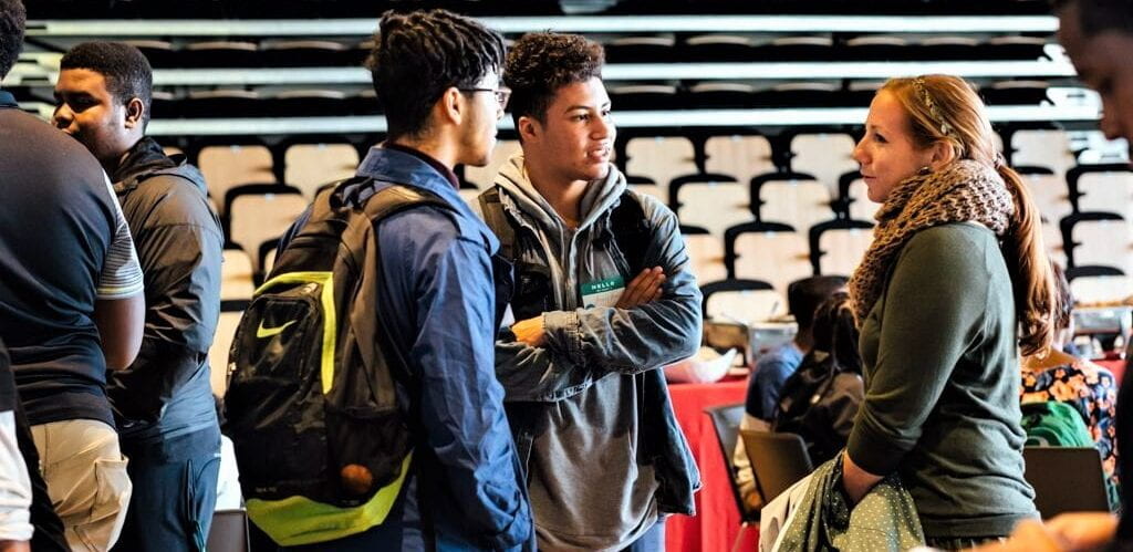 Two college students speaking with an employer at an event.