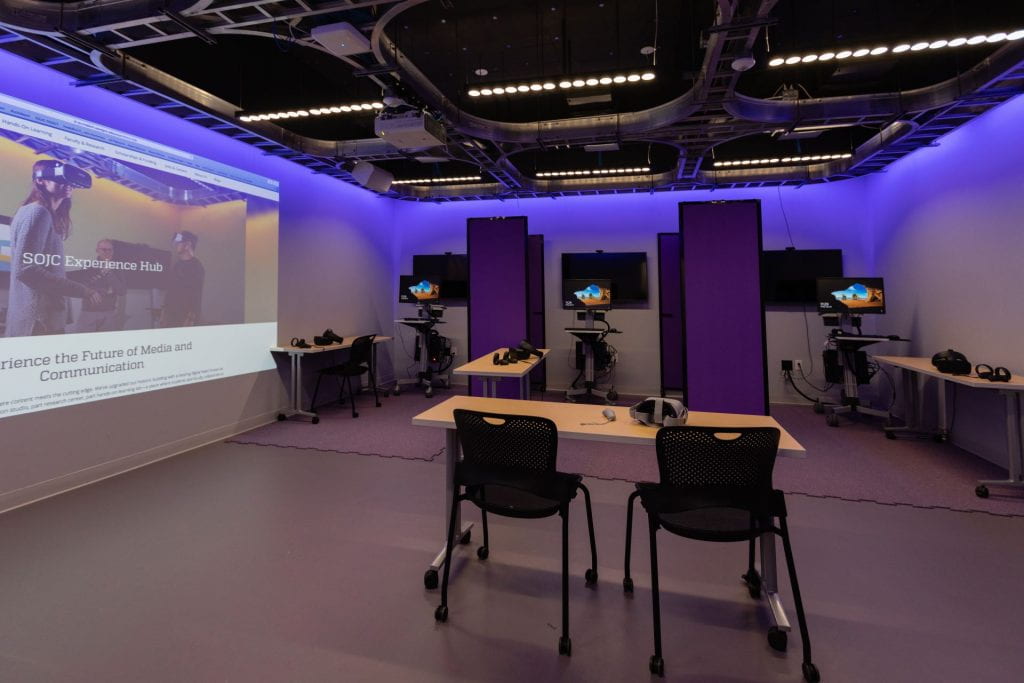A room with three virtual reality headset stations, as well as a large projector on one wall.