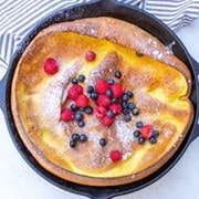 Overhead view of a Dutch Baby topped with with raspberries, blueberries, cinnamon and sugar