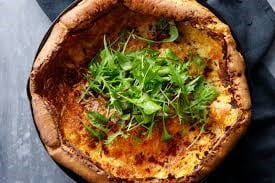 Overhead view of a Dutch Baby topped with greens
