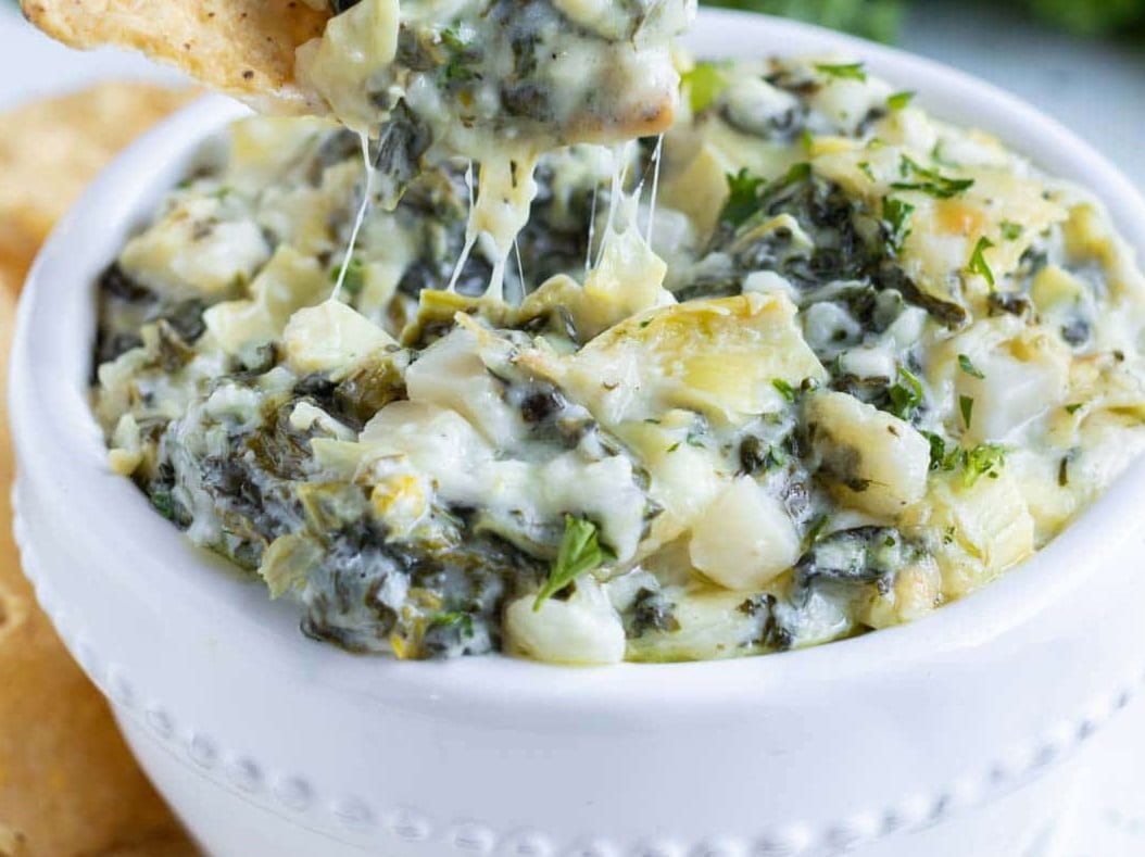 Chunks and pieces of spinach, artichoke, and water chestnuts visible in a white bowl