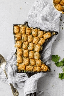 Tater tots arranged in a cast iron dish shaped like Minnesota; laid on a white table cloth