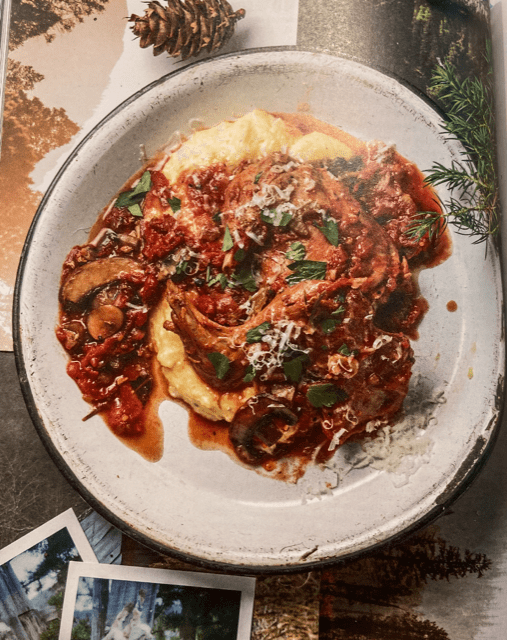 Chicken and mushrooms with tomatoes and parseley in brown sauce over yellow polenta