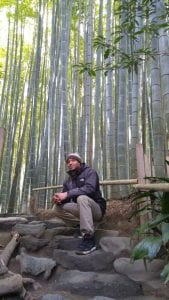 Kaleb sitting on stone steps in front of a bamboo forest 
