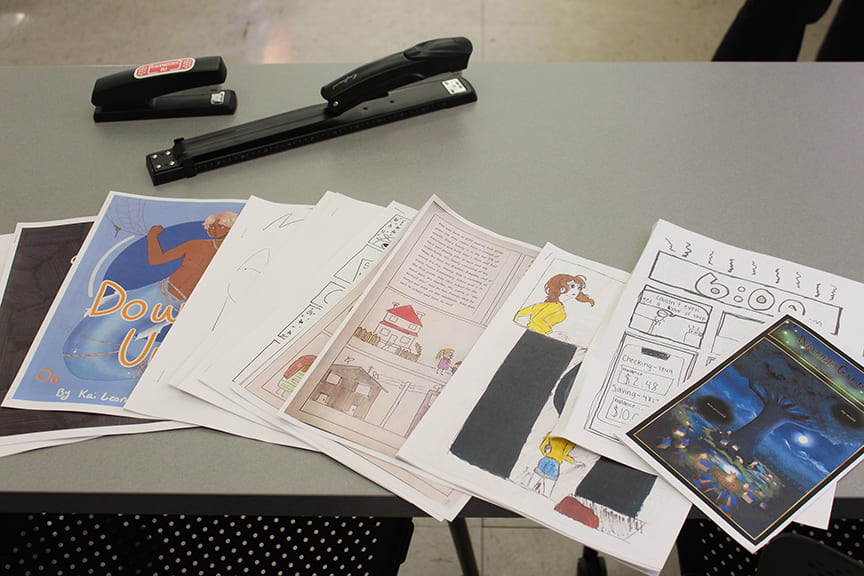 comic projects and staplers lined up on table in classroom