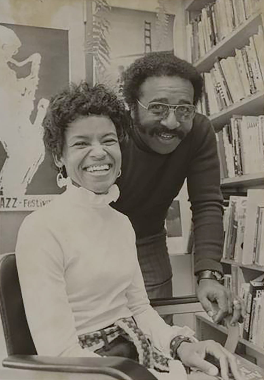 Professor Ed Coleman leans over the shoulder of an unknown woman, both are smiling.