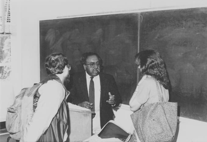 Ed Coleman speaks with two students in a classroom.