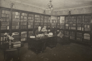 Black and white photo of a man in a book-lined room.