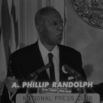 A. Philip Randolph speaks from a podium to the National Press Club.