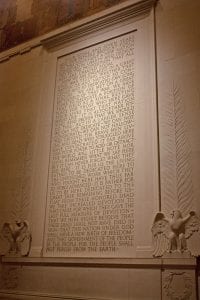 A photo of the text of the Gettysburg Address inscribed on a wall of the Lincoln Memorial, with eagles, wreaths, and palm branches carved in low relief at its sides.