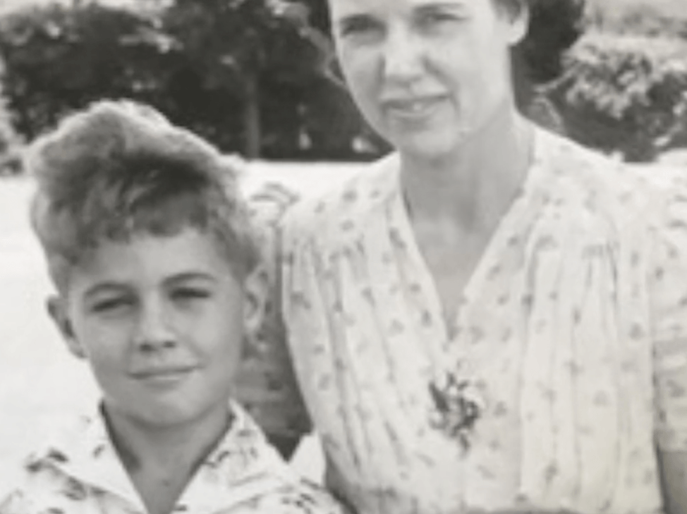 A photograph showing James Blue as a boy standing next to his mother.